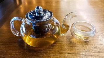 Transparent teapot and a glass on the table. photo