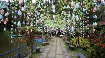 Pathway decorated with plastic accessories and plastic leaves with a lake on the left and ornamental plants on the right. photo