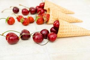 Fresh red cherries in a waffle cone. Ice cream cone with ripe cherries on a white background close-up photo