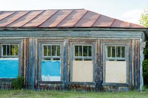 abandoned wooden house with boarded up windows in summer photo