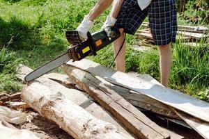 chainsaw in the hands of a worker cutting firewood, close-up photo