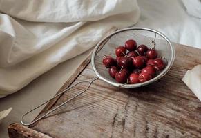 sweet cherry in a metal sieve. Dessert with red berries. Berries on a wooden tray. photo
