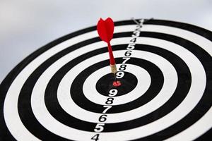 dart arrow hitting in the bullseye center of dartboard. concept of business targeting and aim for business success photo