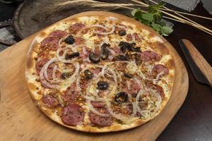 Brazilian pizza with pepperoni, cheese, onion and black olive photo