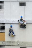 rio, brasil - 04 de noviembre de 2022, pintor trabaja en la recuperación de fachadas de edificios residenciales por cuerda como escalador foto