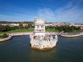 Aerial drone view of Belem Tower in Lisbon, Portugal during a beautiful sunny day next to the river Tagus. Unesco World Heritage. Historic visits. Holidays and summer vacation tourism. Colorful palace photo