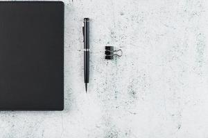 Office desk with black notepad and pen on gray background. Top view with copy space. photo