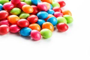 A rainbow of color from multicolored candies close-up, multi-colored glaze dragee on a white background photo