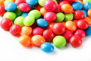 A rainbow of color from multicolored candies close-up, multi-colored glaze dragee on a white background photo