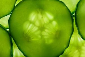 Slices of green fresh cucumber backlit as a textural background photo