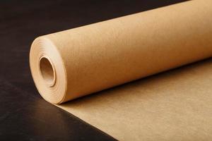 A roll of unfolded brown parchment paper, for baking food in on a dark background, top view. photo