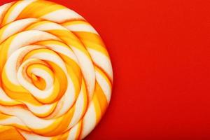 Colorful round Lollipop, on red background. Minimal concept with copy space. photo