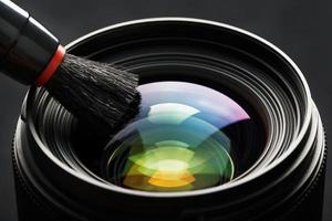 Brush cleaning the camera Lens with a beautiful close-up optical unit. photo