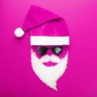 Cap, Santa Claus with black glasses and a beard of snow on a pink background. photo