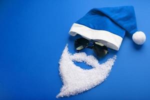 Cap, Santa Claus with black glasses and a beard of snow on a blue background. photo