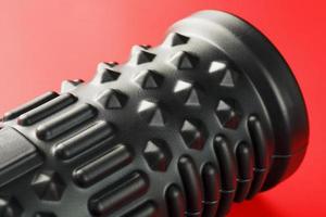 Black lumpy foam massage roller on red background. For the mechanical and reflex effects on tissues and organs. photo