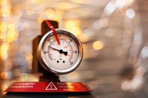 High pressure gauge in the oil system of industrial equipment, pumps and pipelines with a red line photo