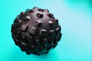 Black bumpy foam massage ball is a rubber ball on a blue background. photo