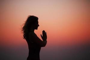 mujer deportiva practicando yoga en el parque al atardecer - haciendo namaste de saludo de mano. luz del atardecer, hora dorada, destellos de lentes. libertad foto