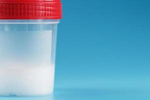 A container for biomaterials with sperm analysis and a red lid on a blue background. photo