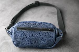 Waist bag made of blue leather, banana on a gray background. photo