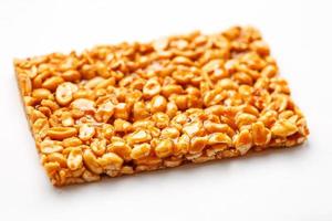 A large tile of roasted peanuts bar in a sweet molasses on a white background. Kozinaki useful and tasty sweets of the East photo