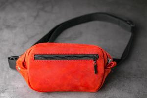 Red waist bag made of leather, banana on a gray background. photo