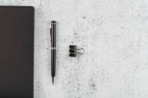 Black Notepad with a black pen on a gray background photo