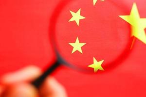 The People's Republic of China a flag is watched through magnifying glass. Spies and observation of People's Republic of China. Monitoring of a condition of China photo