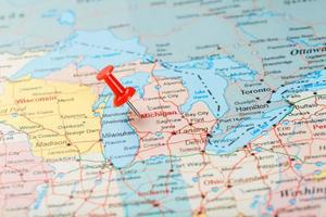 Red clerical needle on a map of USA, Michigan and the capital Lansing. Close up map of Michigan with red tack photo