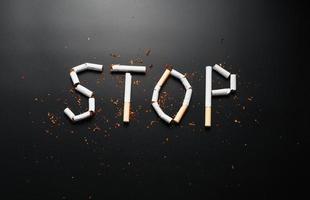 The inscription STOP from cigarettes on a black background. Stop smoking. The concept of smoking kills. Motivation inscription to quit smoking, unhealthy habit. photo