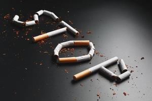 la inscripción se detiene de los cigarrillos en un fondo negro. deja de fumar. el concepto de fumar mata. inscripción de motivación para dejar de fumar, hábito poco saludable. foto