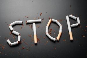 la inscripción se detiene de los cigarrillos en un fondo negro. deja de fumar. el concepto de fumar mata. inscripción de motivación para dejar de fumar, hábito poco saludable. foto