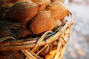 Coconuts in a wicker basket of brown color with fibers lit by sunlight. Stack on the market photo