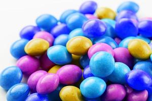 A rainbow of color from multicolored candies close-up, multi-colored glaze dragee on a white background photo