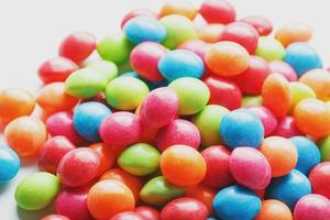 A rainbow of color from multicolored candies close-up, multi-colored glaze dragee on a white background photo