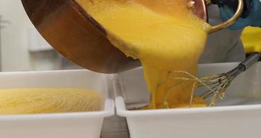 Pouring Hot Custard Cream Into Plastic Baking Pans - close up, panning right shot video