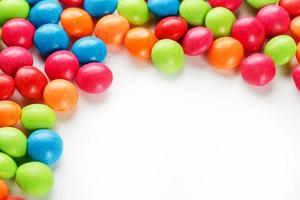 A rainbow of color from multicolored candies close-up, multi-colored glaze dragee on a white background photo