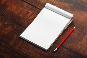 Notepad with red pencil on a brown wooden table background, for education, write goals and deeds photo