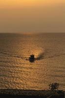 Fishing boats are sailing in the sea and was approaching the shore in the evening sunset with golden sun shining brightly atmosphere warm and romantic. Landscape natural sea travel journey concept. photo