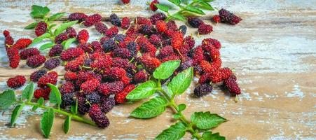 Fresh Mulberry's organic is a healthy super fruit source of vitamins on the old wooden background. mix mulberry fruit in Thailand.