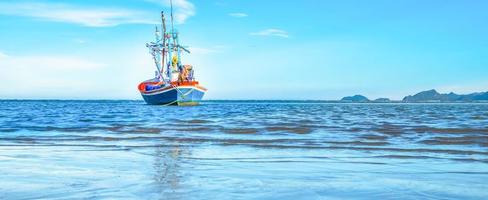 A view of a fishing boat moored by the sea in the morning with a beautiful blue sea and sky. photo