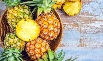 Top view of Sliced and half Pineapple and fresh pineapple fruit placed on an basket wooden photo