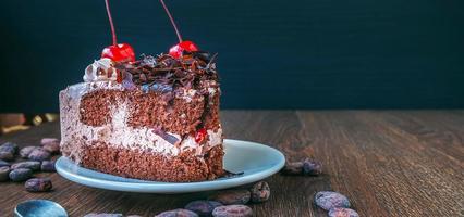 trozo de tarta de queso de chocolate en un plato y granos de cacao en una mesa de madera, vista superior sobre un fondo rústico de madera foto