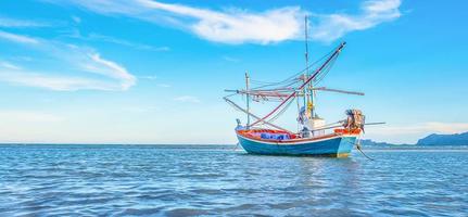 A view of a fishing boat moored by the sea in the morning with a beautiful blue sea and sky. photo