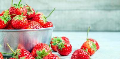 Close up of fresh red strawberries in a bowl on a blue old wooden background photo