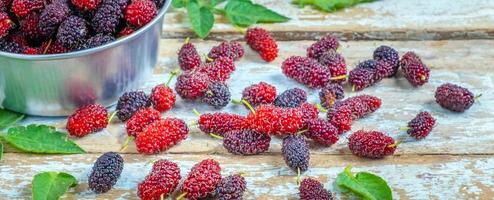 la morera orgánica fresca es una fuente saludable de vitaminas en el viejo fondo de madera. mezclar fruta de morera en tailandia. foto