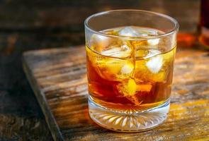 Close up of A glass of liquor with ice cubes on a wooden table photo