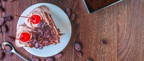 Slice of chocolate cheesecake on plate and cocoa beans on wooden table, above view over a rustic  wood background photo