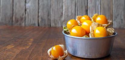 Close-up ripe yellow Cape Gooseberry fruit In a bowl stainless steel on a wooden background